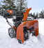 orange and black snow blower outside ready to clean up snow
