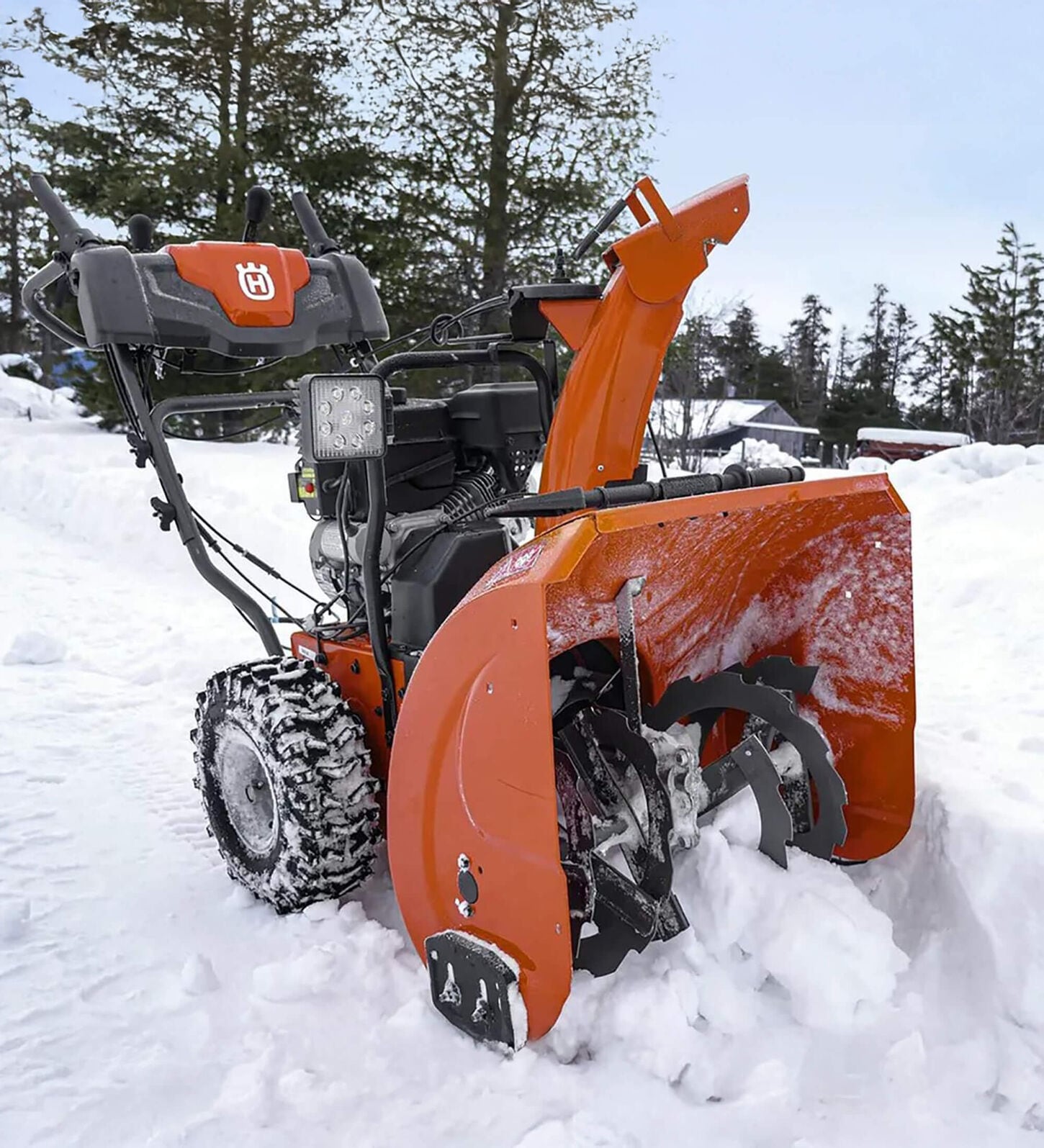 orange and black snow blower outside ready to clean up snow
