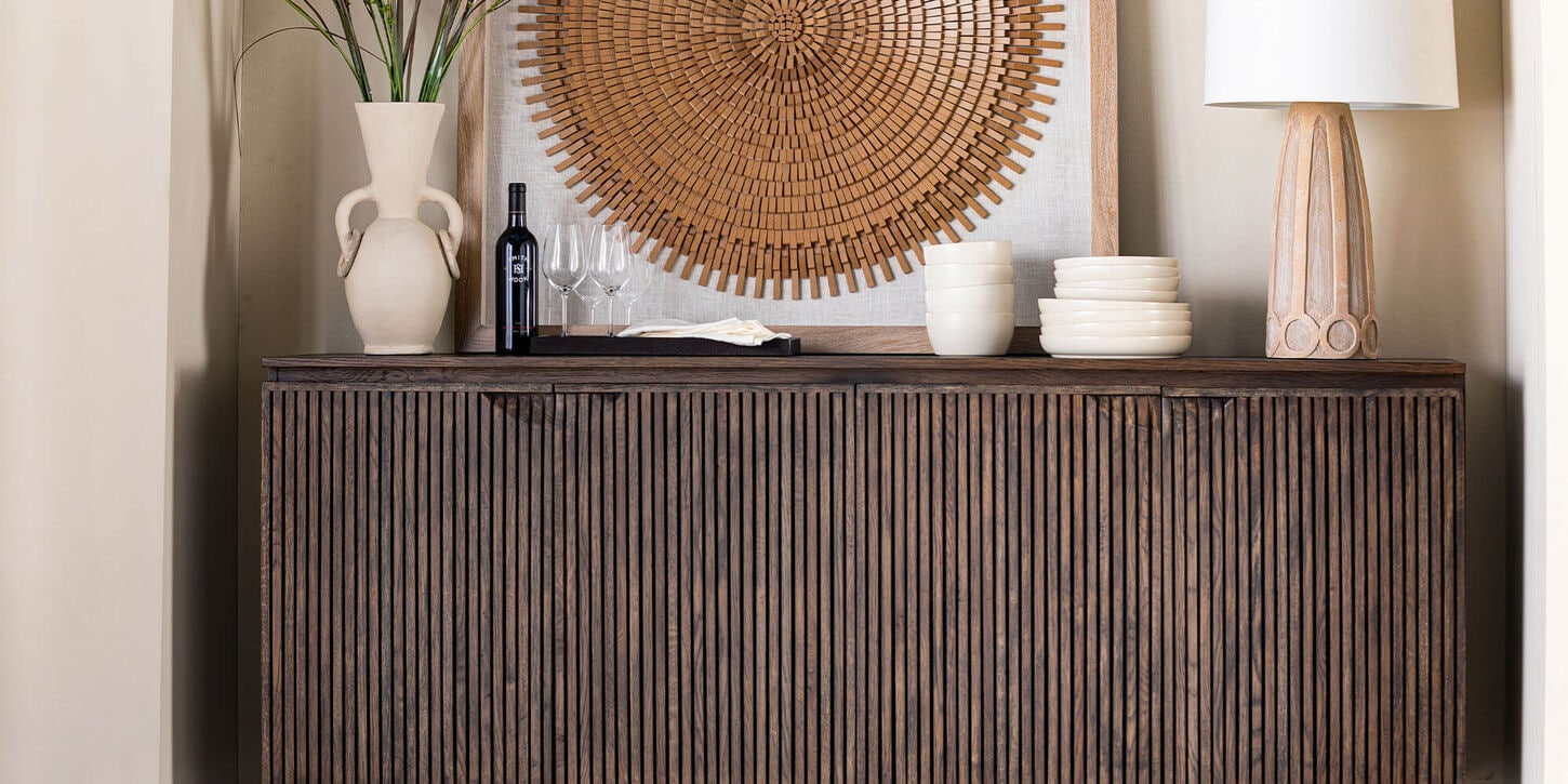 Credenza with earthy brown tones and a piece of art work with greenery in vase and other decor items