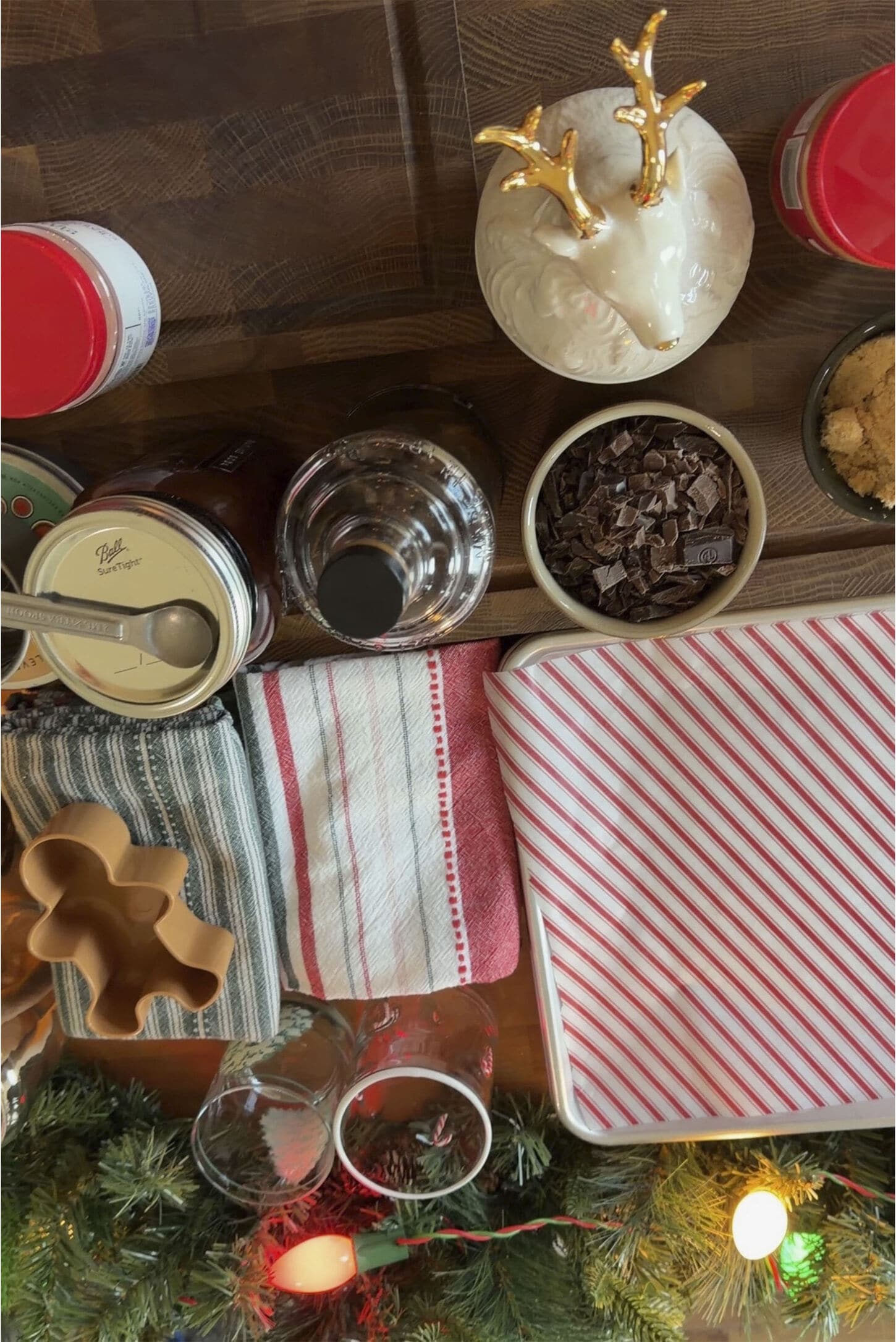 Baking set up in kitchen with various measuring cups, baking towels, and christmas decor