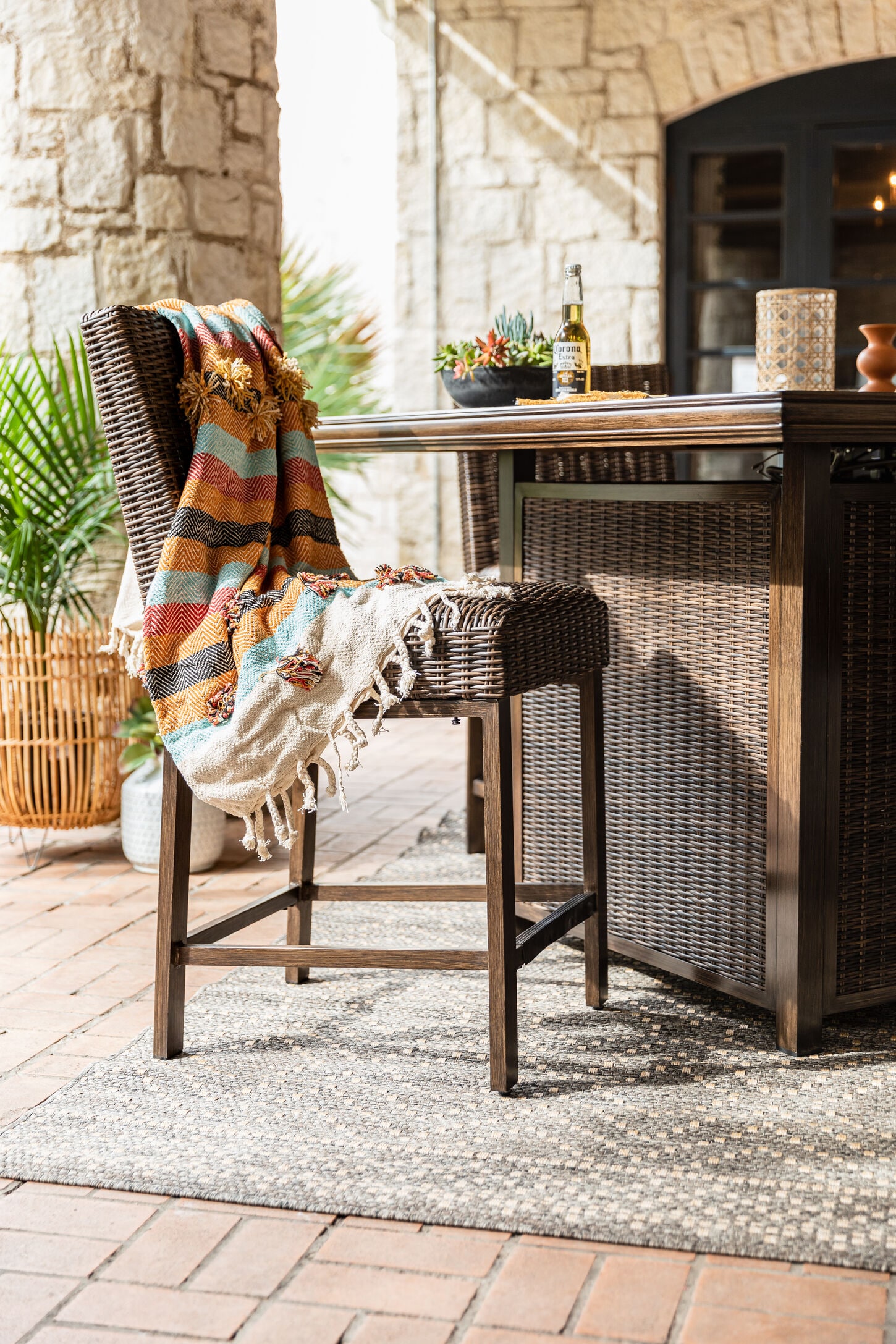 Outdoor patio area with a rug, bar, barstool and fall inspired blanket and decor