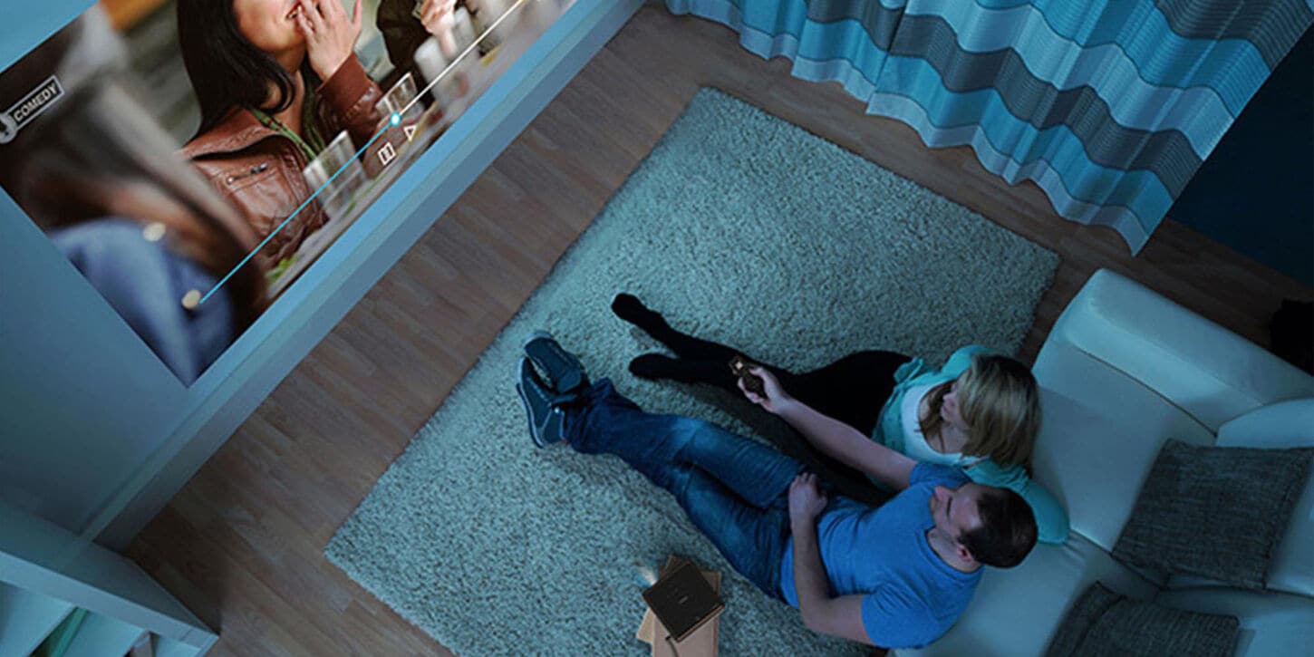 epson projector showing a movie on the wall with a couple sitting on the floor watching