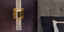 Lighting wall scone with gold accents in bedroom with purple walls to create moody look