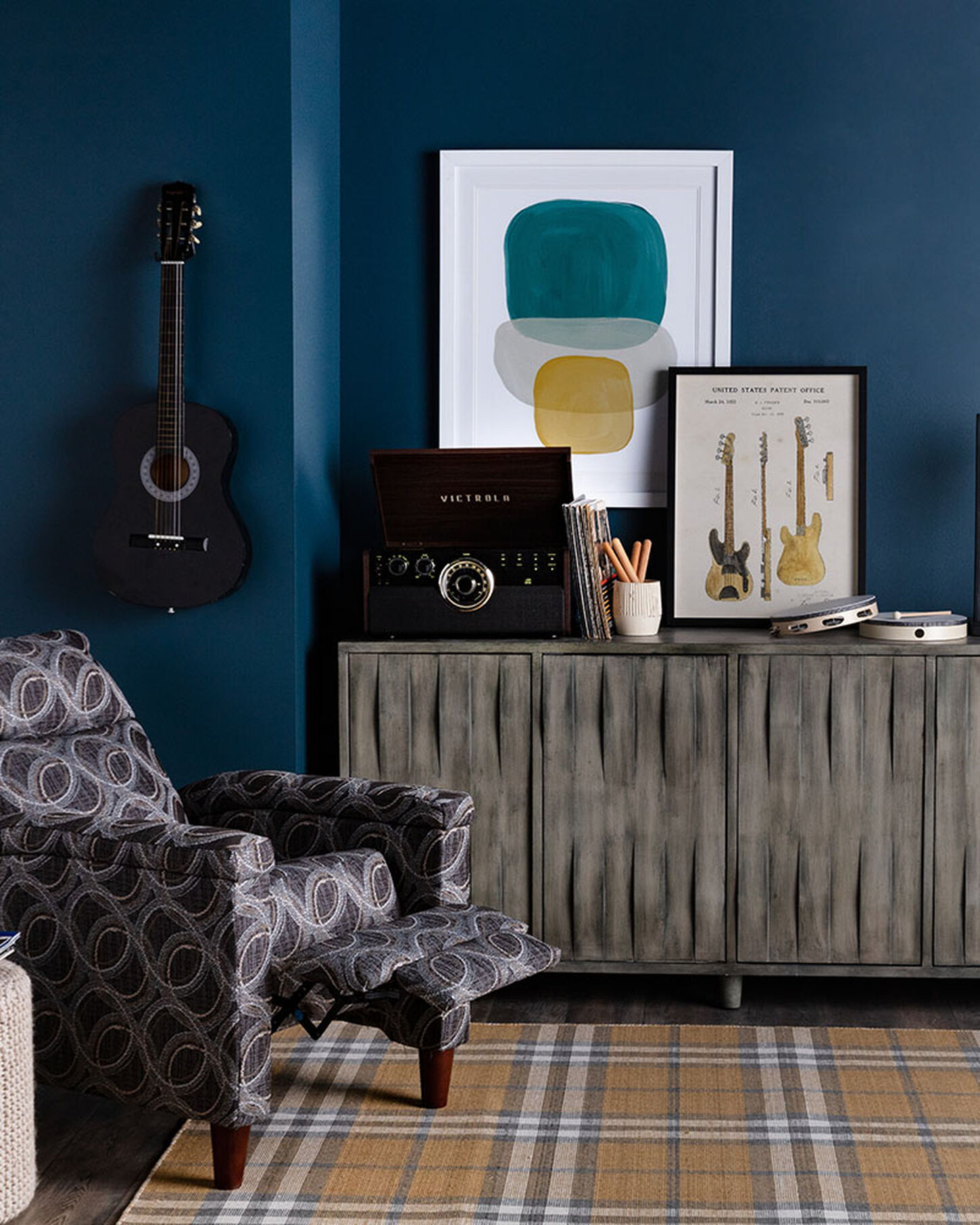 Dark office space with blue walls and lots of pictures and a guitar on the wall
