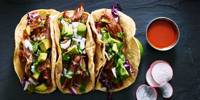 Set of three tacos with avocado, radish and more.