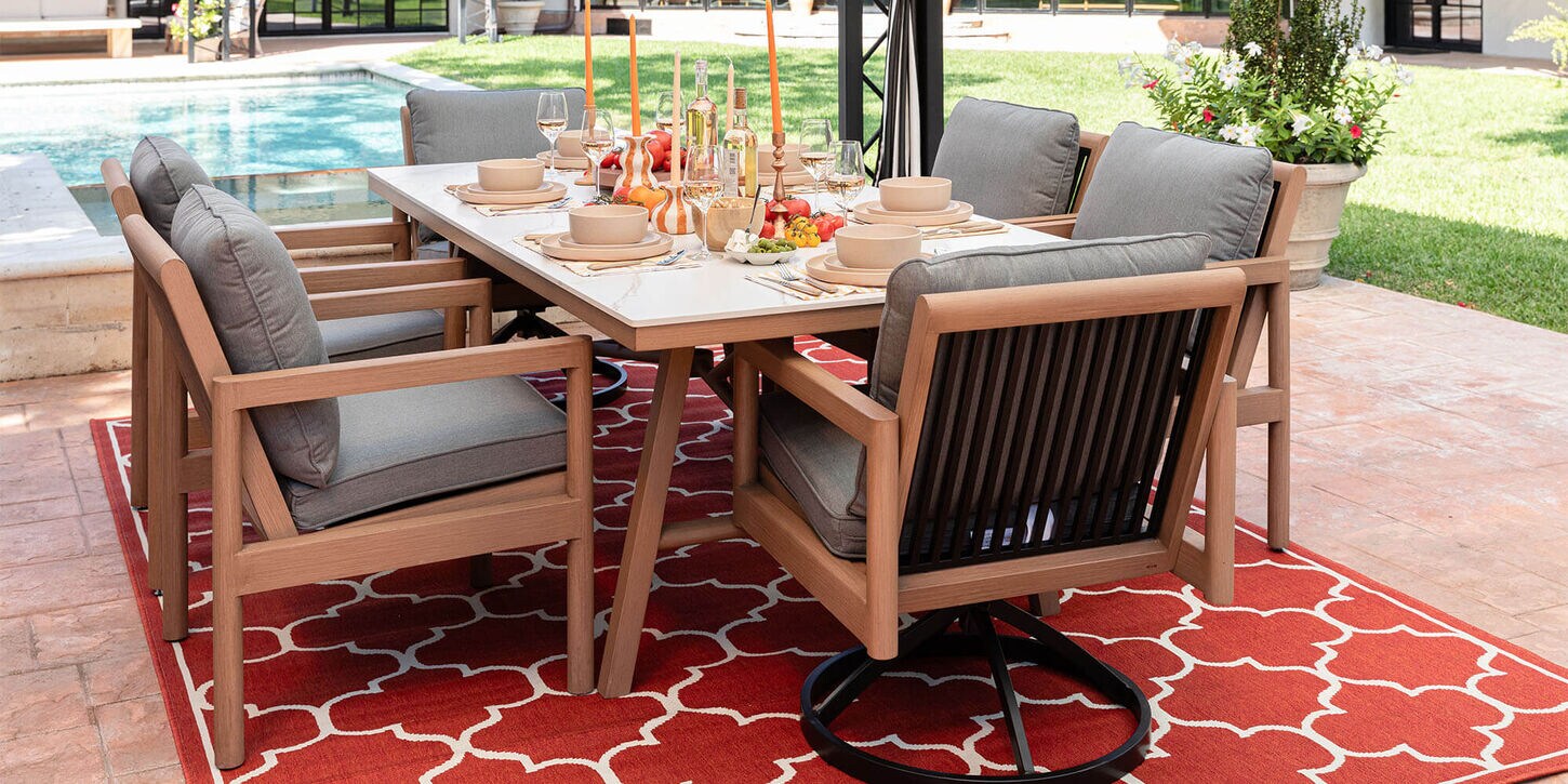 Outdoor patio furniture with a dining table, chairs, and a large area rug