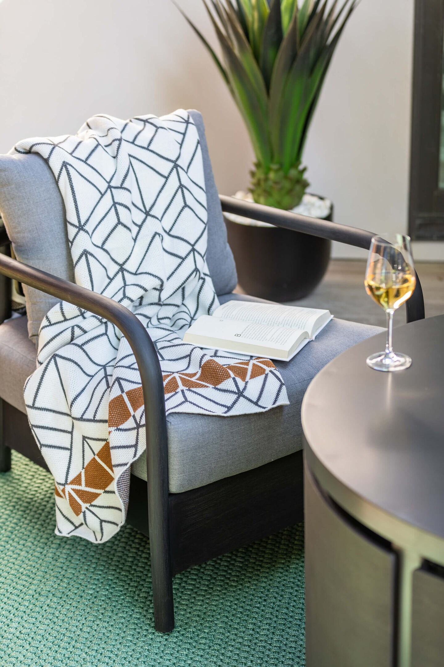 Light gray patio chair with firewood in the corner and snacks on the coffee table