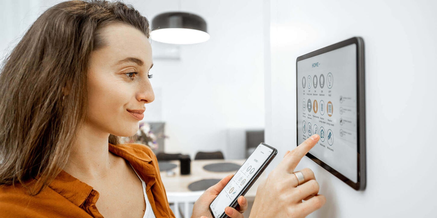 Woman using her phone and smart technology in her home that is on her wall