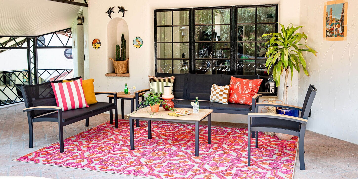 Outdoor patio furniture with a rug, pillows, and decor