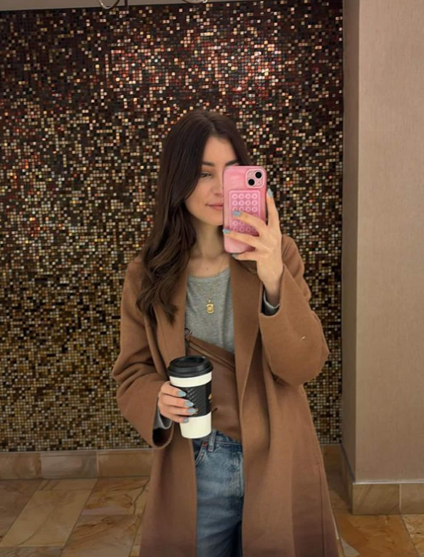 megan taking a selfie in the bathroom mirror holding a coffee cup