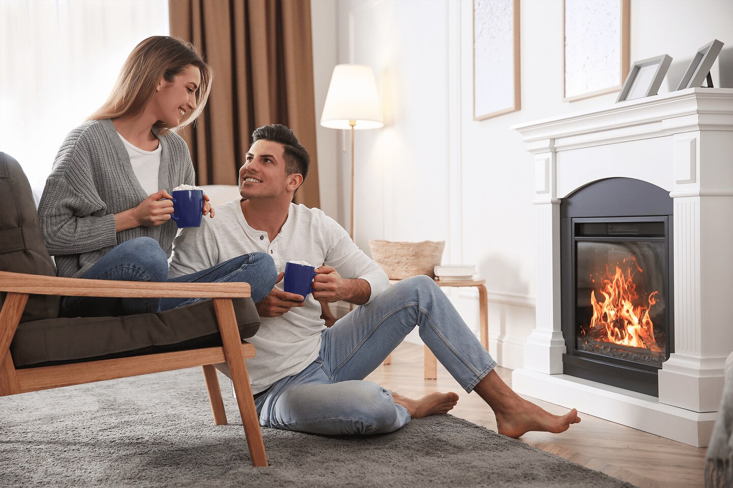 Two people sitting by a warm fire with coffee cups.
