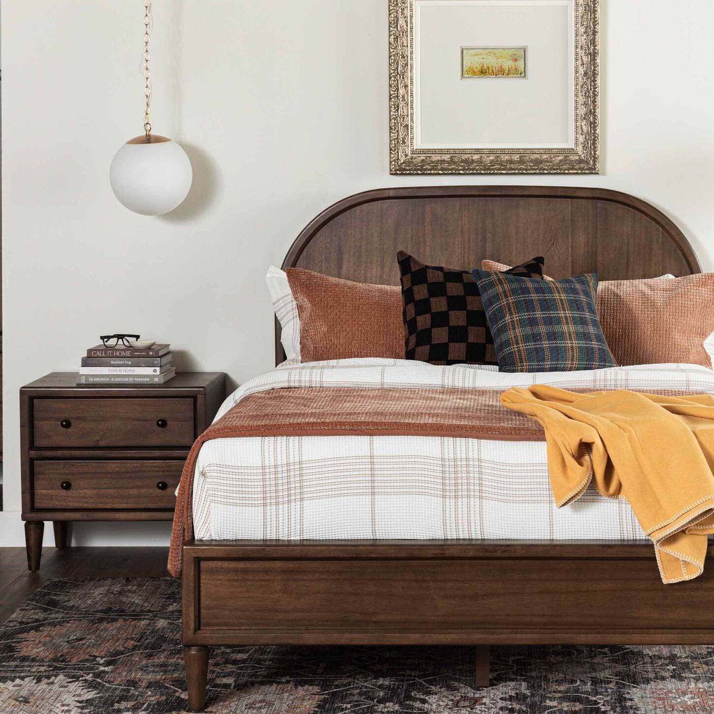 Dark wood bed and nightstand in a bright bedroom with fall pillows