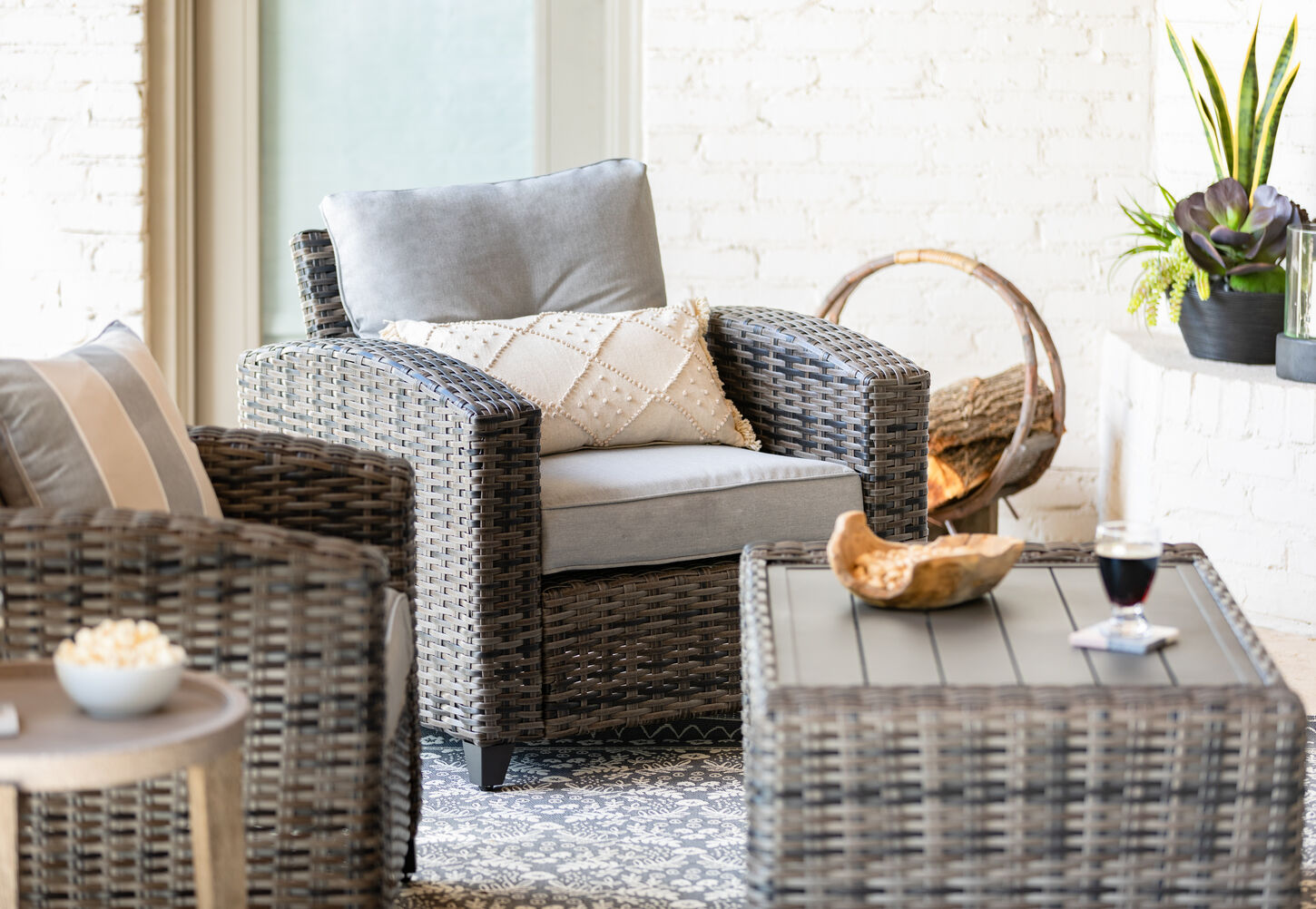 Light gray patio chair with firewood in the corner and snacks on the coffee table
