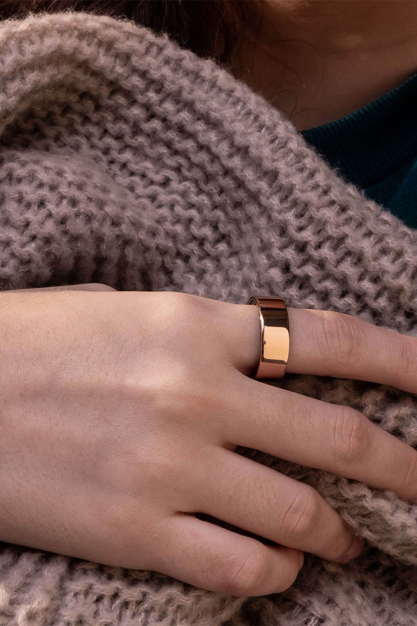 Oura ring and a woman wearing it under a blanket