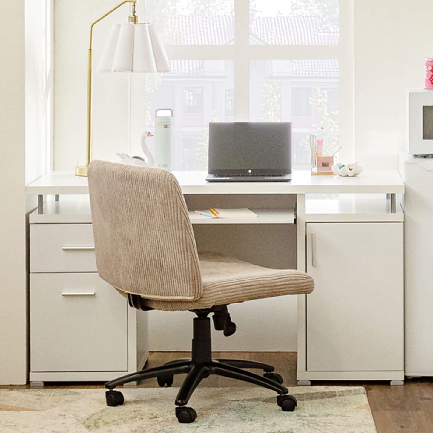 White desk in dorm room with tan chair