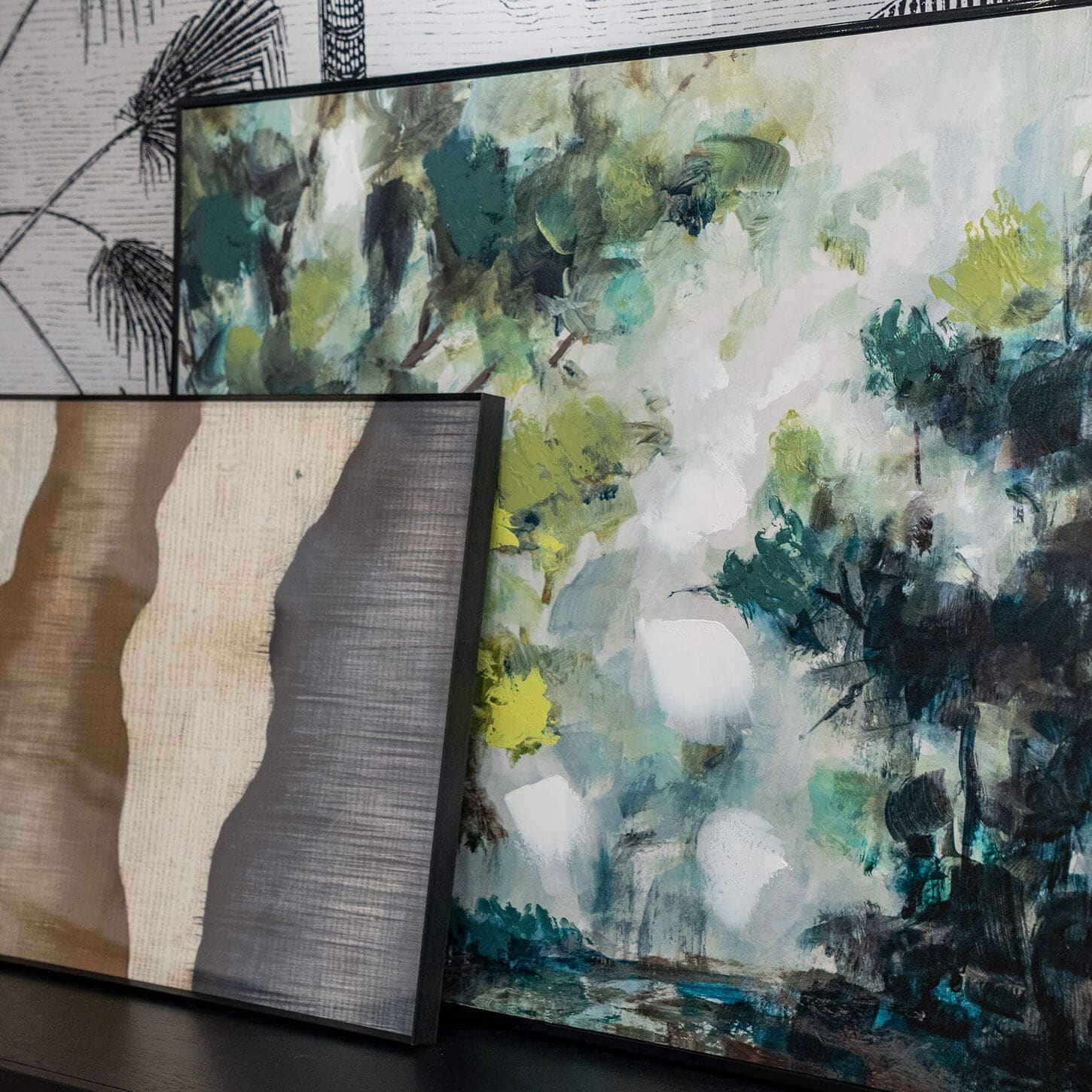 Two modern paintings stacked next to each other sitting on a credenza