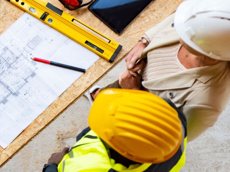 A group of people wearing hardhats discussing blueprints