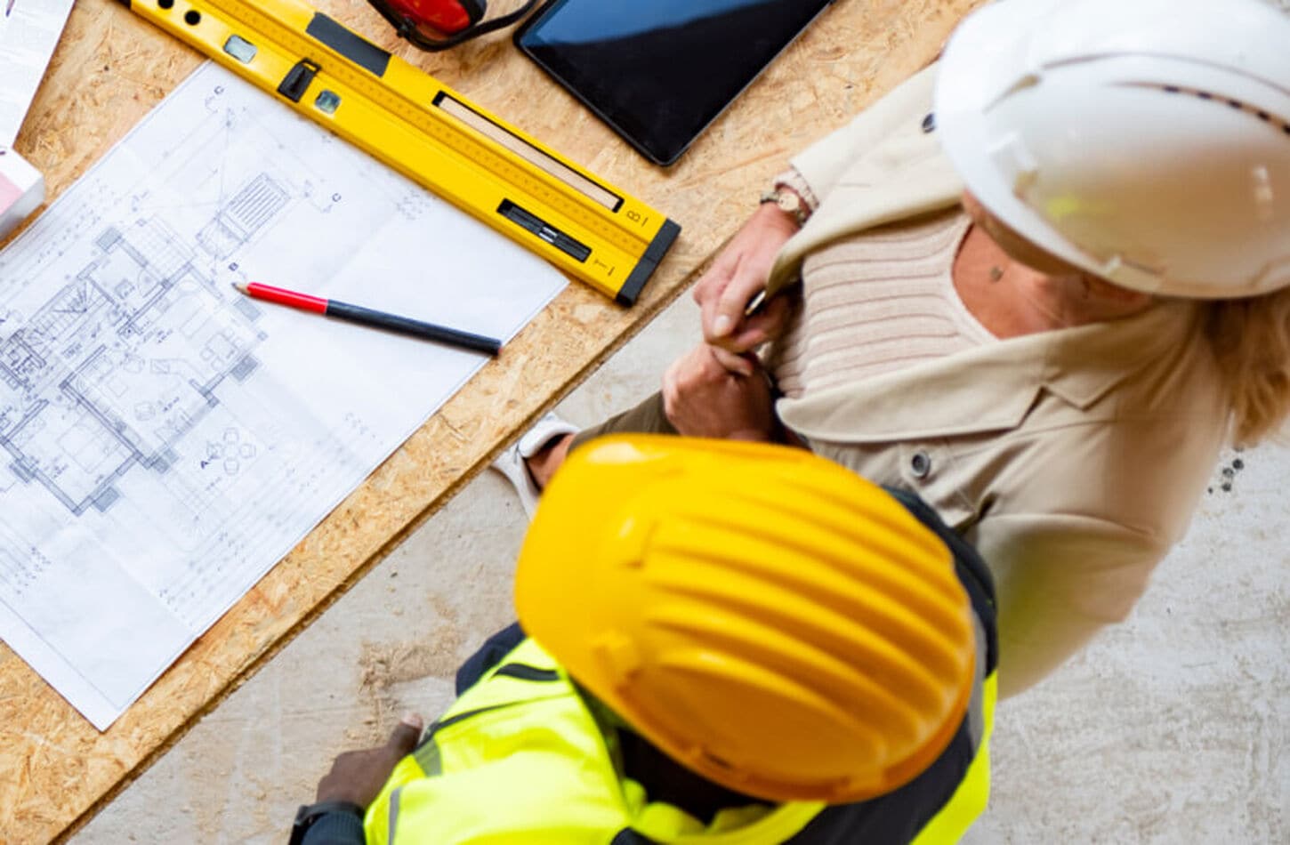 A group of people wearing hardhats discussing blueprints