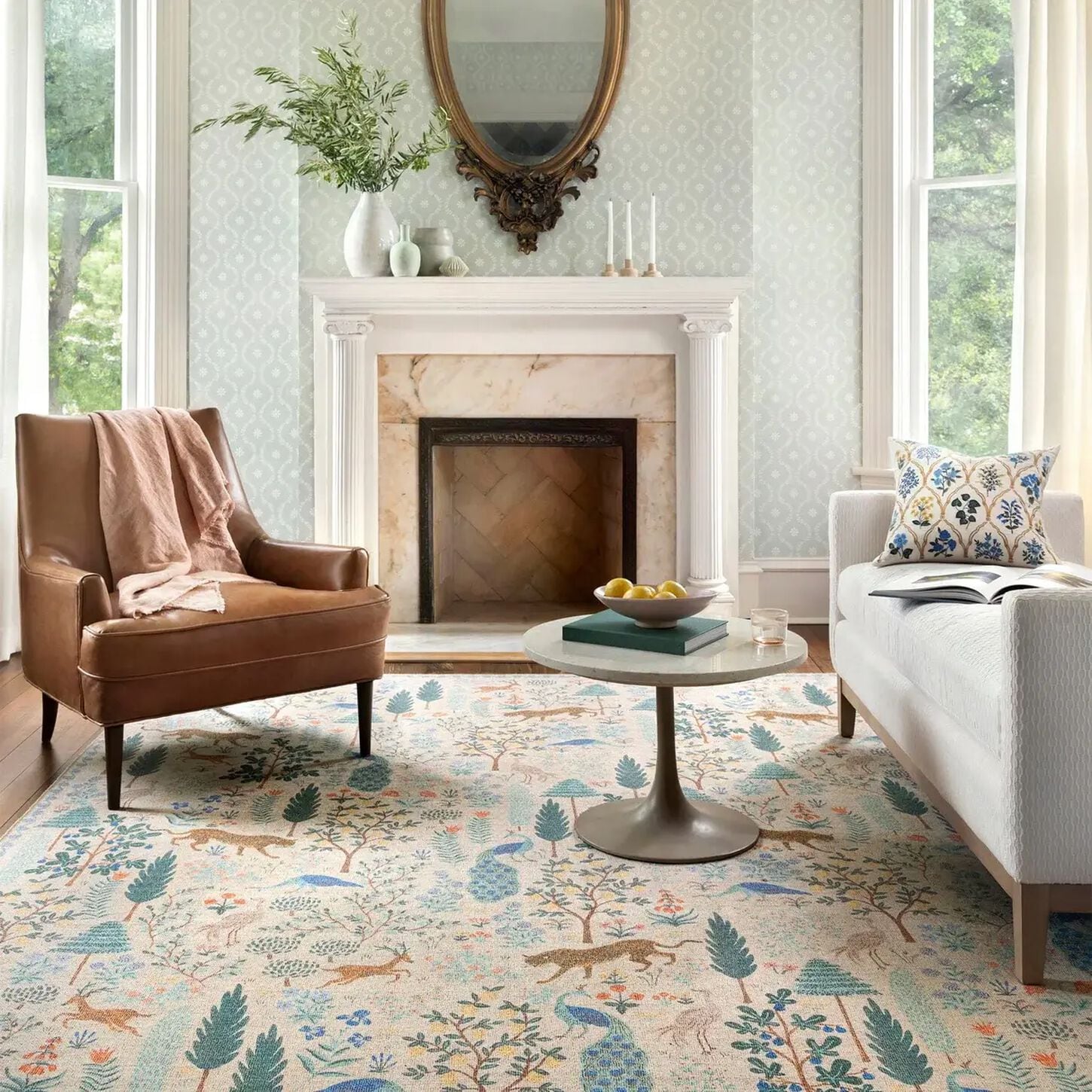 Rifle Paper Company rug displayed in living room with fireplace, sofa and chair