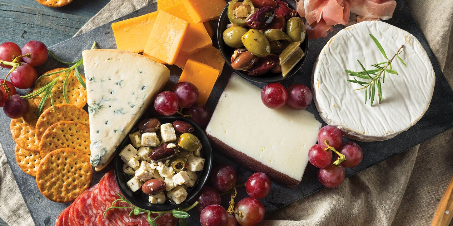 Charcuterie board full of cheeses, crackers, and fruit