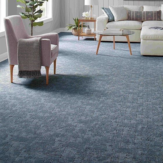 Blue patterned carpet in a living room with white sectional and a tan side chair