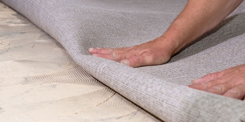 Man laying carpet roll on floor