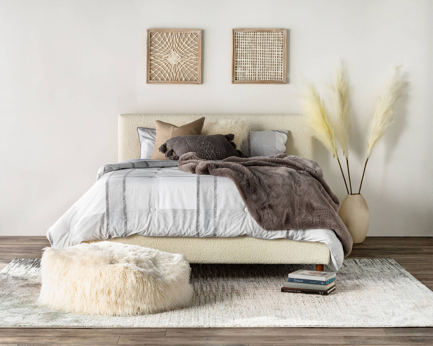 A cozy bedroom with white bedding and pampass on the side of the bed.