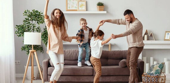 Family dancing together in living room with children