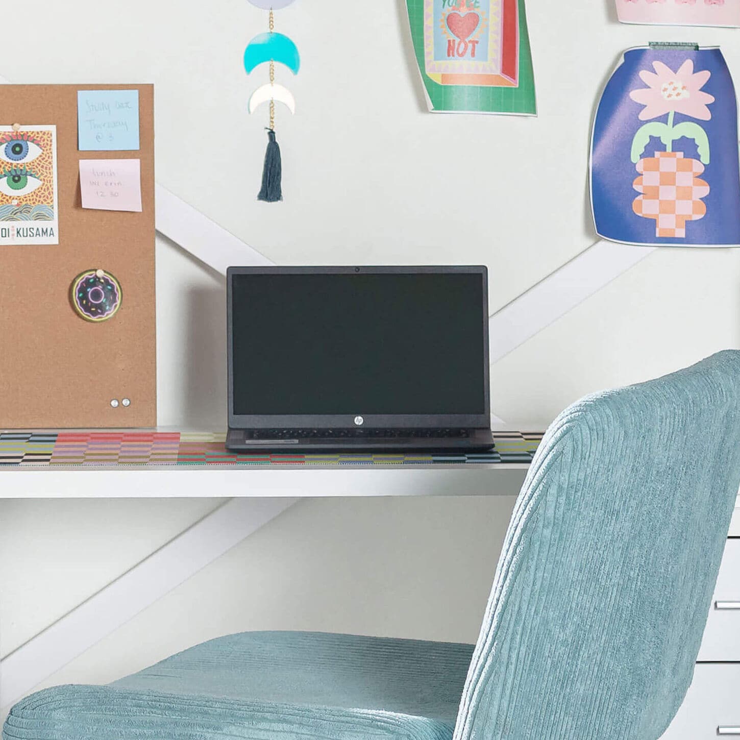 Laptop on a desk in a dorm room with blue office char