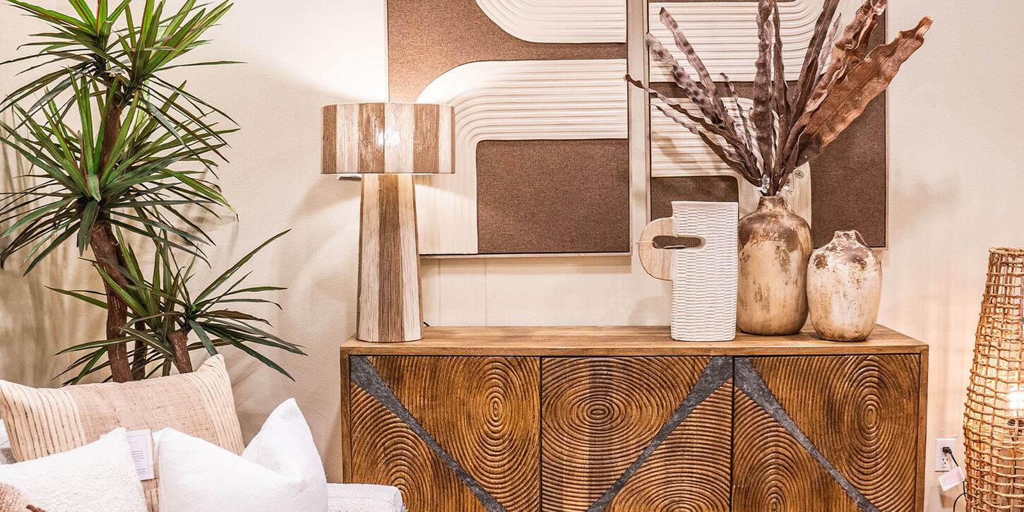 Entry way table with lots of decor including a lamp, plant and artwork