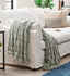 warm green throw blanket laid over the side of a white sofa
