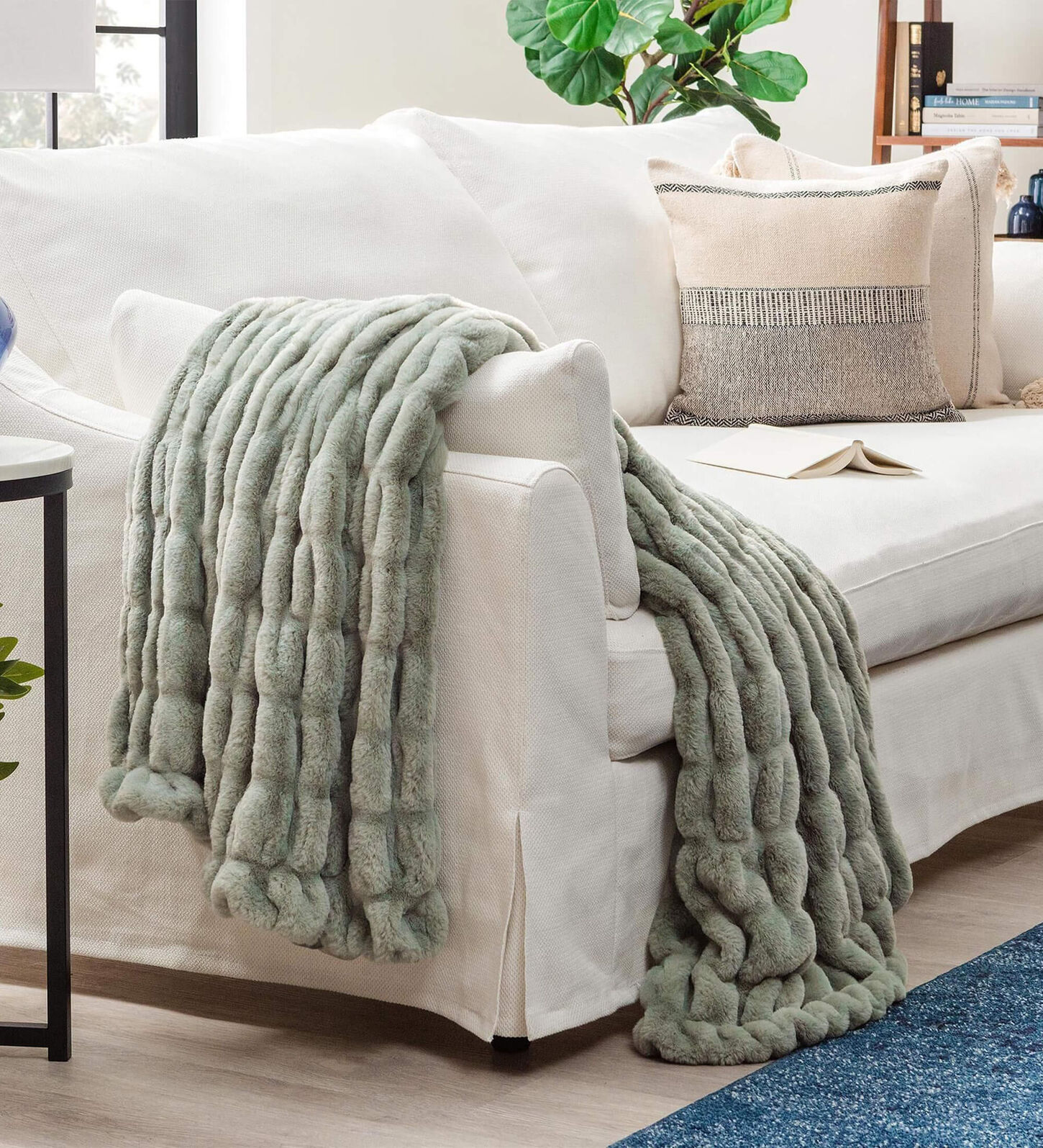 warm green throw blanket laid over the side of a white sofa