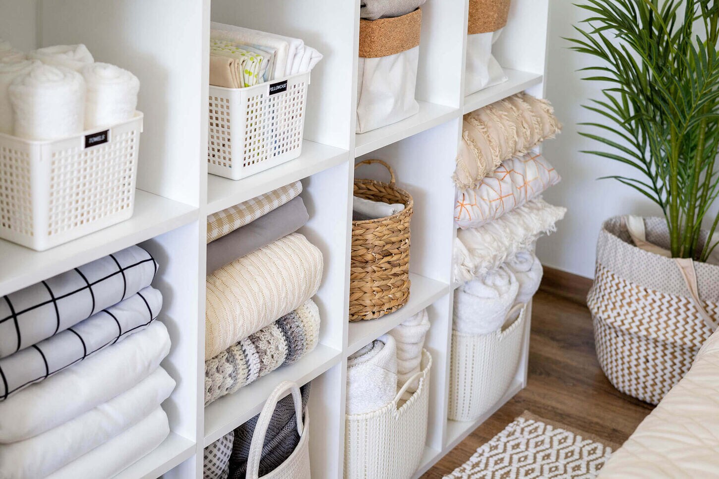 White cube shelf with organized home items - towels, sheets, and more.