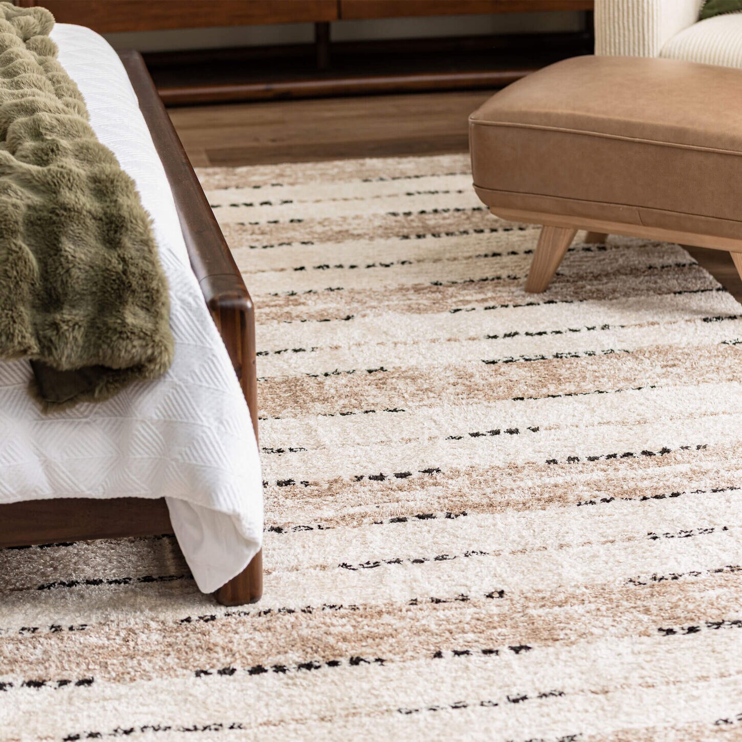 Cream and tan colored area rug in bedroom