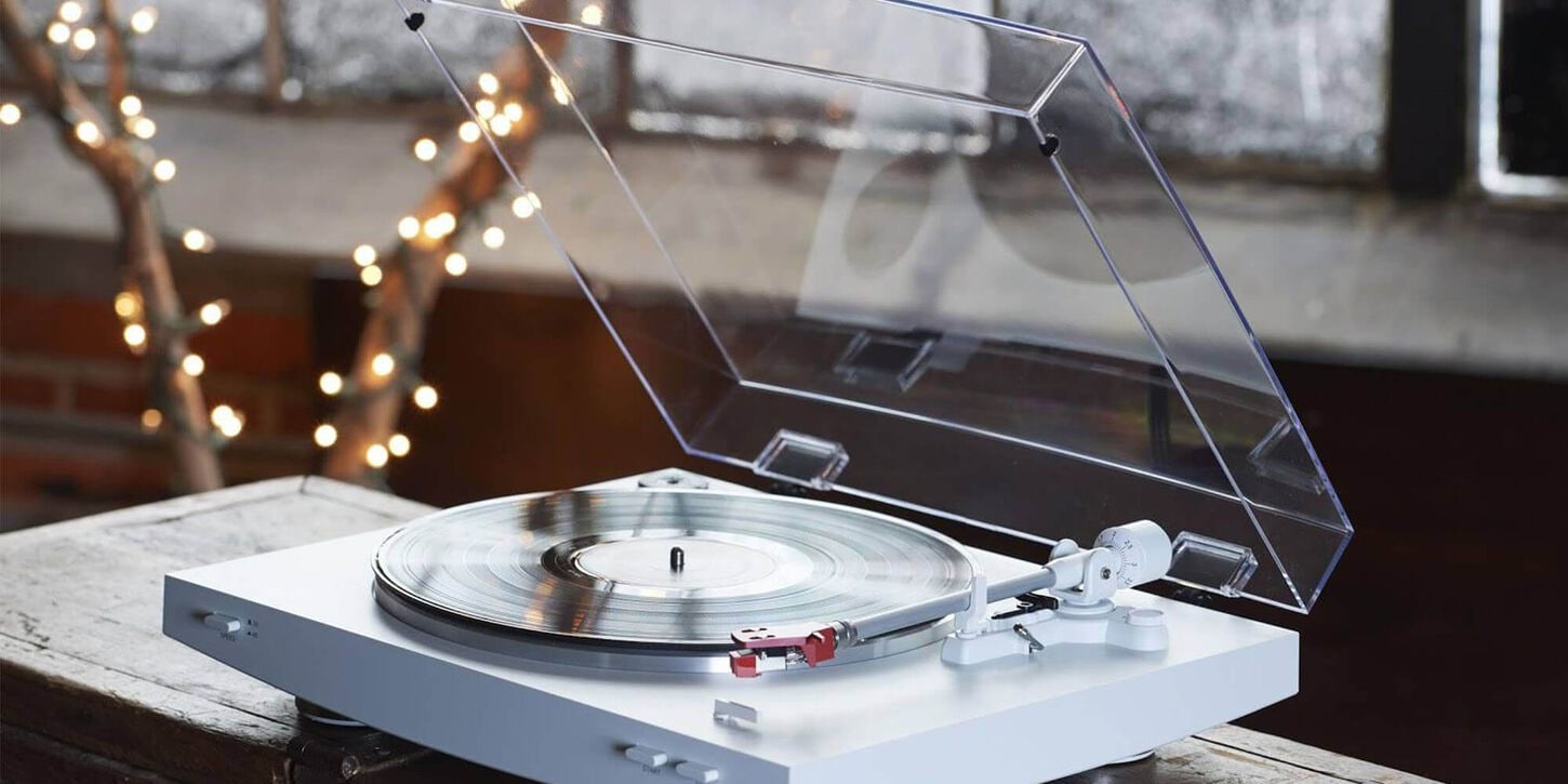 Vinyl record at a wedding sitting on a table with lights hanging from a tree in the background
