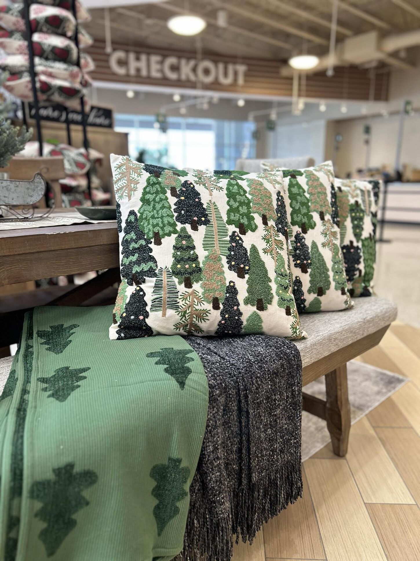 christmas tree pillow and blanket with trees on a bench
