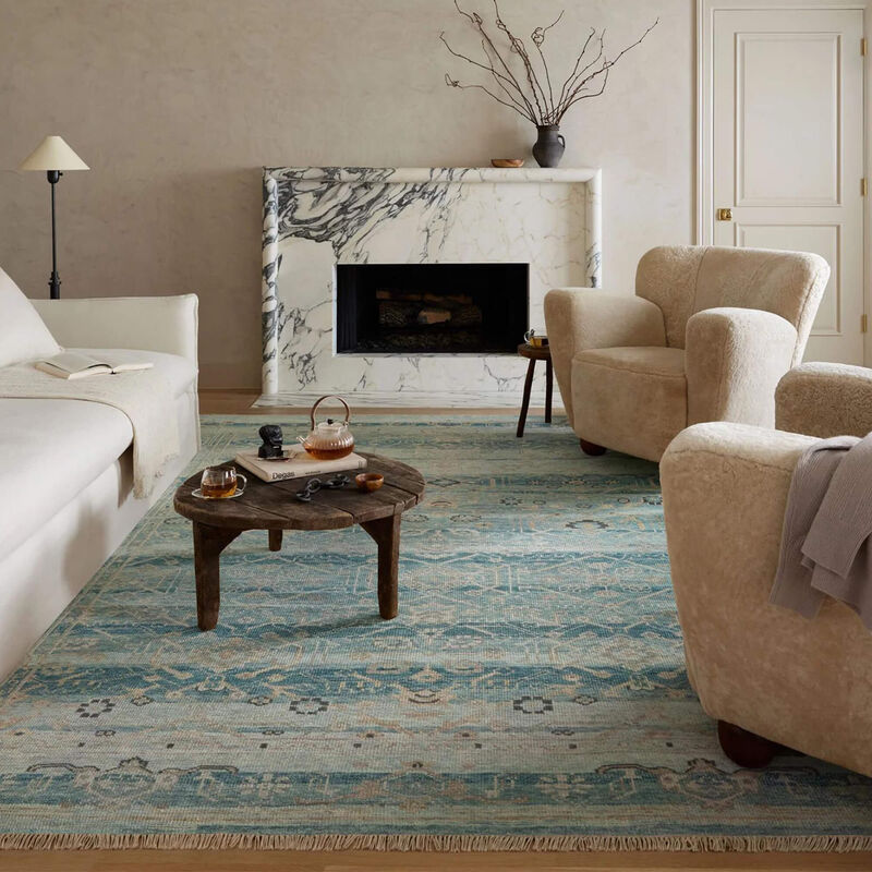 living room with two beige chairs a white couch on a tan and green hand made area rug