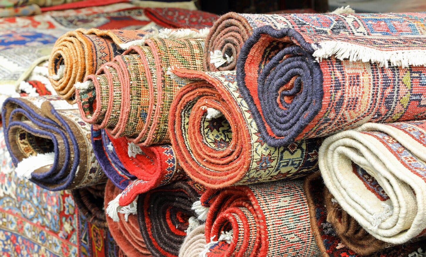 Various rug designs rolled up and placed together in a pile