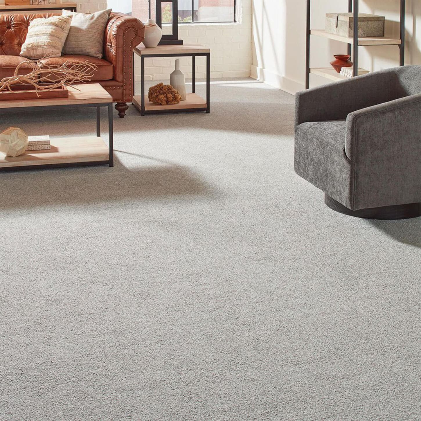 living room with a brown couch and a gray chair on a tan and black speckled carpet