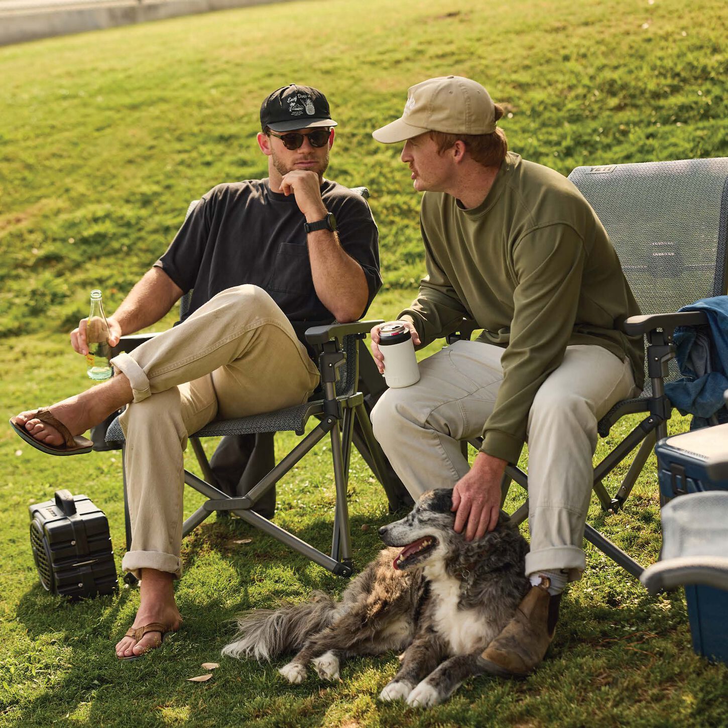 two men sitting on yeti outdoor chairs in a green grass field