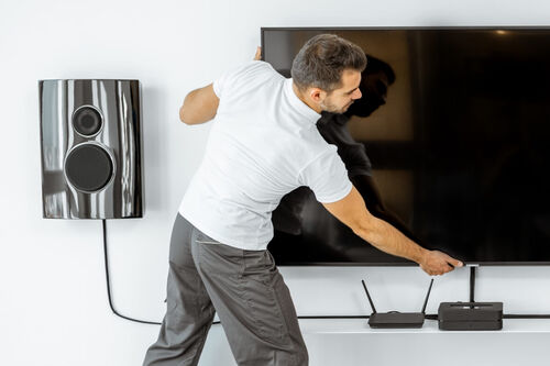 Man installing mounted TV and sound system