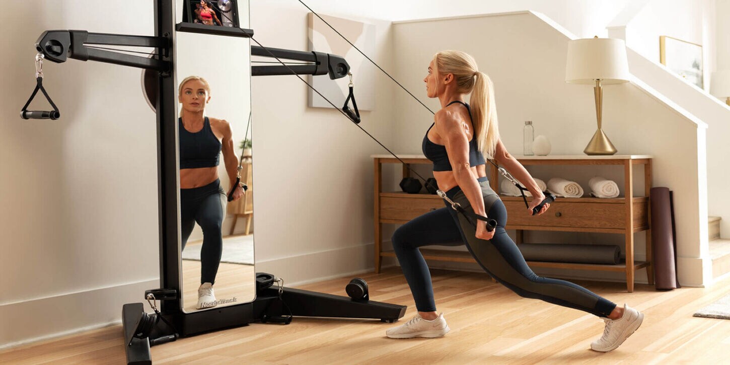 Woman using a home gym in her living room with furniture against the wall.