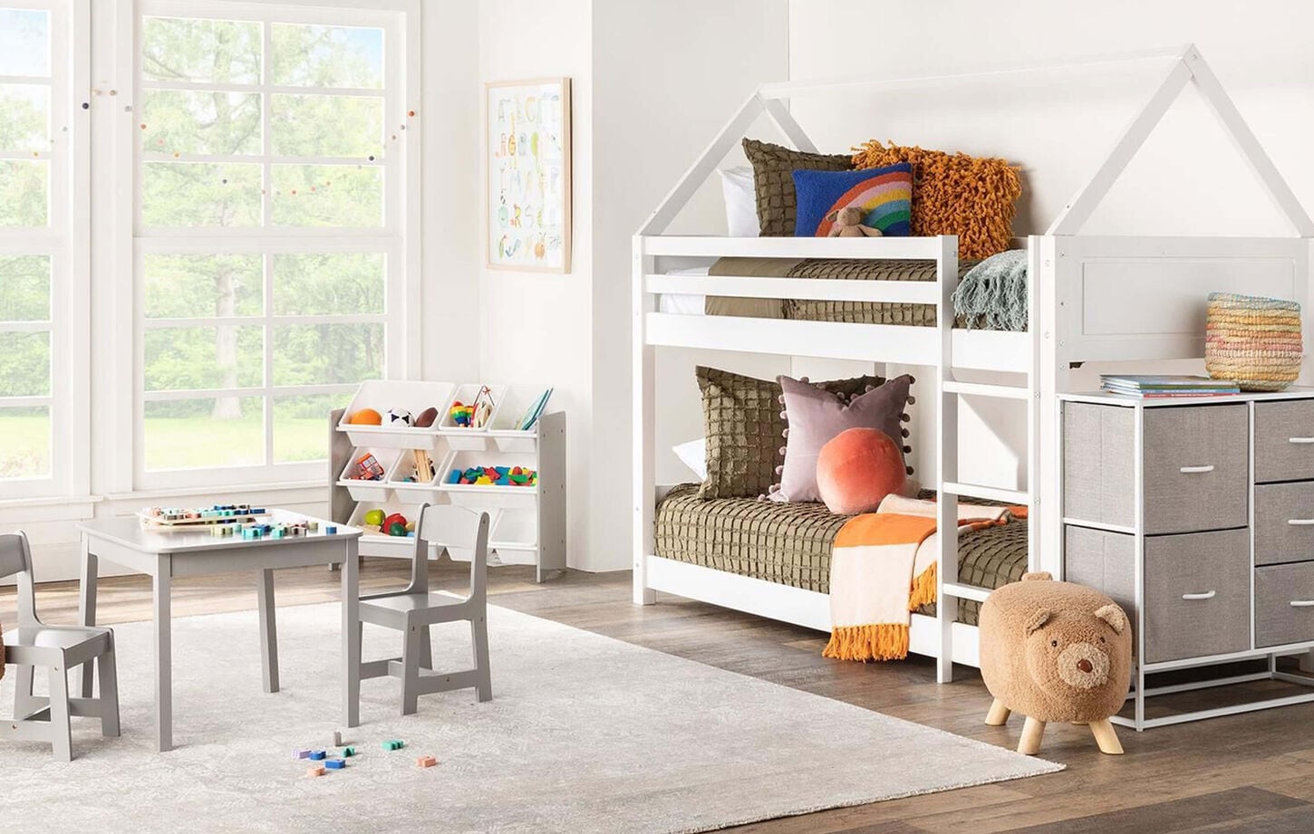 Kids bedroom with white bunk bed, table and chairs and toy storage bin