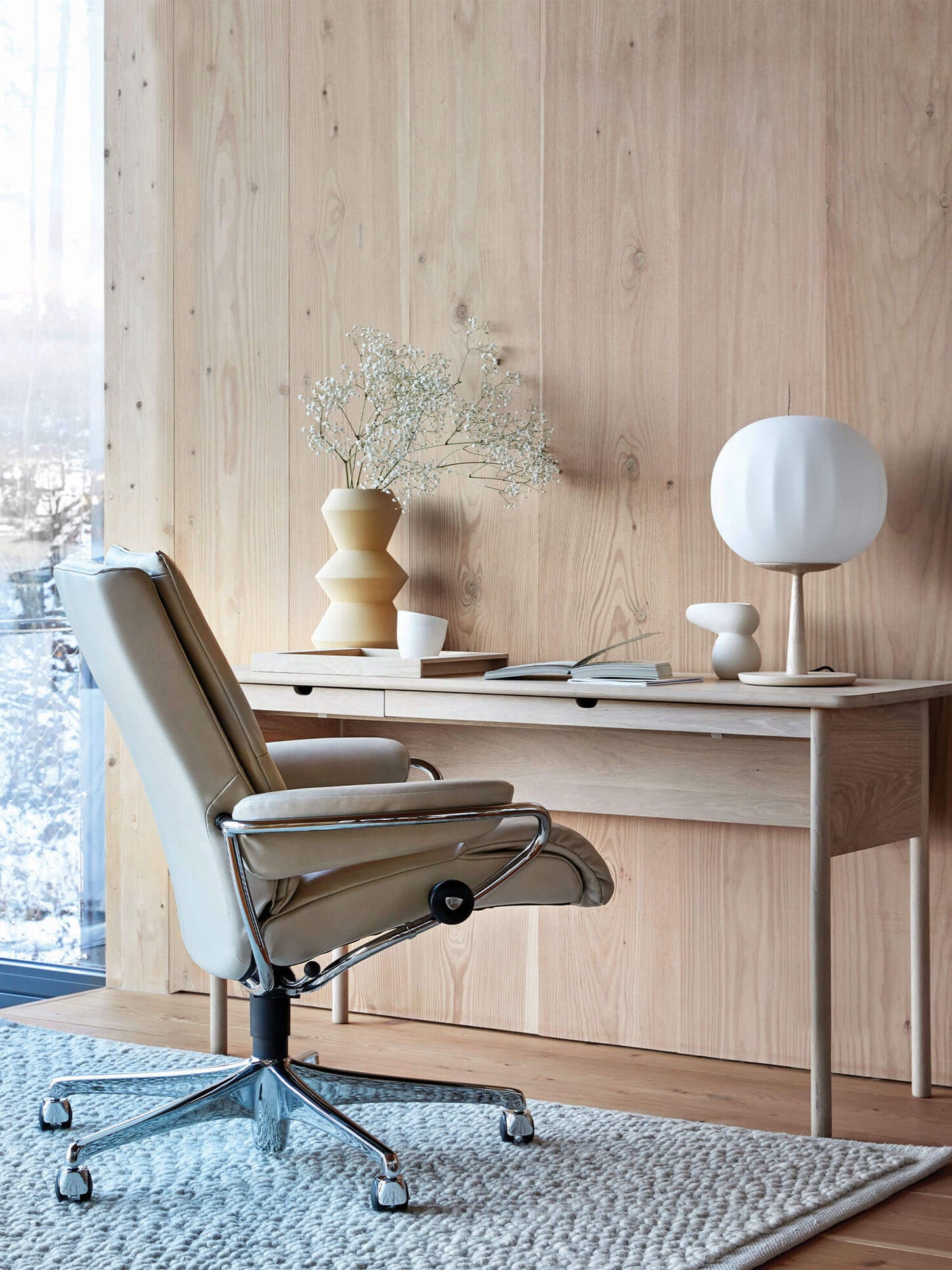 Light office furniture with a big window and decor featuring a rug