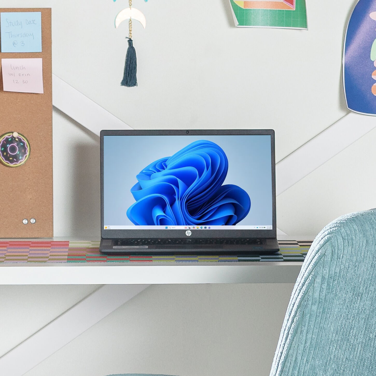 Laptop on a desk in a dorm room with blue office char
