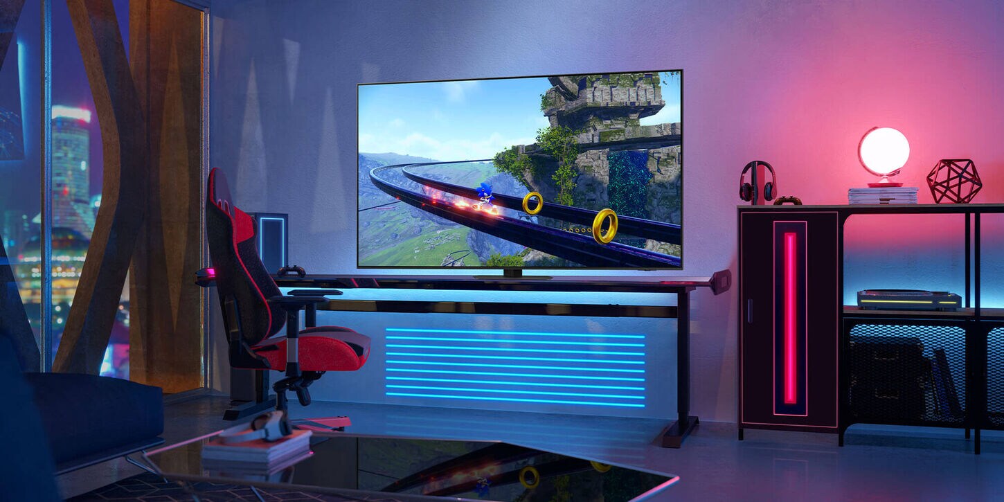 Gamers stream room with a giant screen on a desk, gaming chair, lamp, and decor