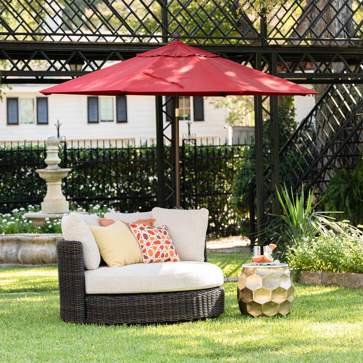 Red patio umbrella protecting a round outdoor chair in a backyard