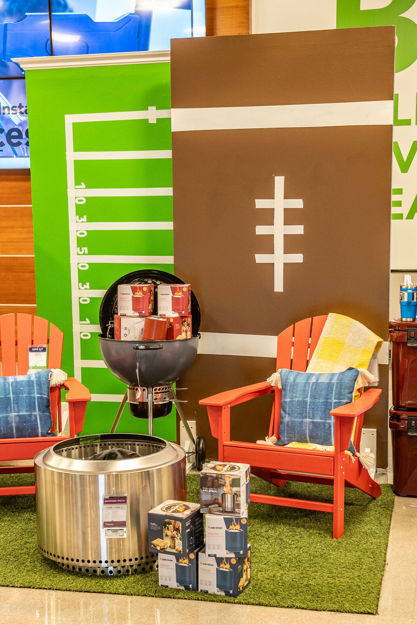 Tailgating setup with backdrops, chair, firepit, grill, and turf