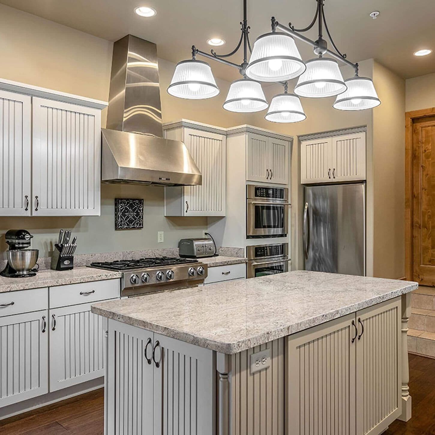 White quartz countertop on an island in a tidy kitchen with stainless appliances