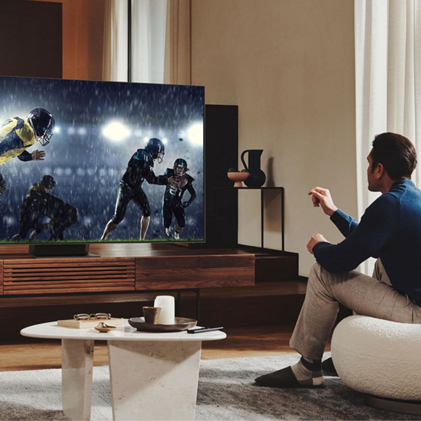 Person on sofa watching football on tv